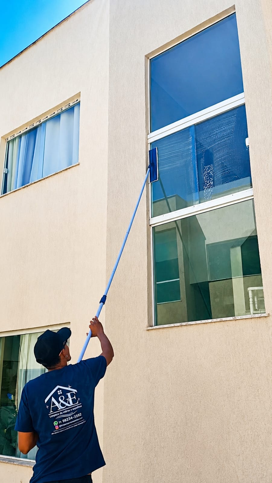 Profissional da A&E limpando janela de fachada residencial